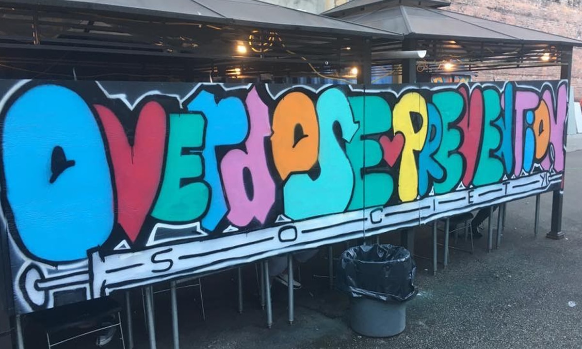 Graffiti spelling out overdose prevention on a wall